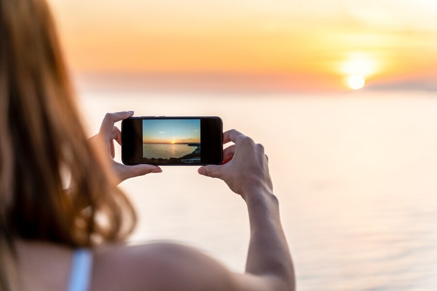 jovem mulher fotografando um por do sol na praia com seu telefone celular 77593 295 Click and Play - Agência de Vídeo Digital - Produtora Audiovisual